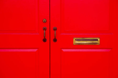 Red wooden door with golden door handle and golden door knocker.の写真素材