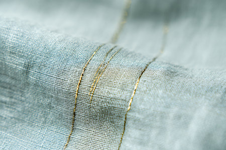 Closeup detail of light blue fabric texture background with golden thread.の素材