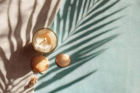 Candle, seashells and palm leaf shadow on blue and white backgroundの素材