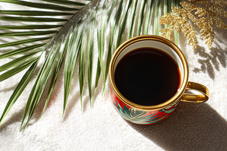 Cup of coffee with tropical palm leaves and snowflake on white towelの素材