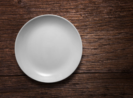 Blank white ceramic round dish on wooden desk background with copy spaceの写真素材