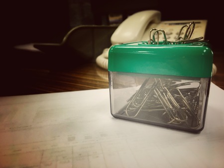 Paper clip into the clip box on the working tableの写真素材