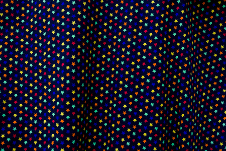 Abstract  geometric pattern with multi color stars on a black background.A star on a fabric surface movement.の写真素材
