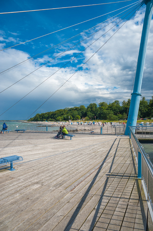 The pier Flunder with tourists at the beach of Hohwacht at the Baltic Seaの写真素材