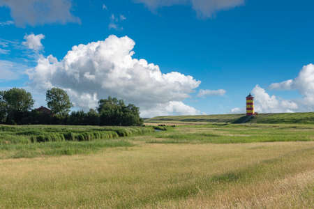Dike landscape with Pilsum lighthouse near Pilsum. Pilsum is located in East Frisia on the German North Sea coast.の写真素材
