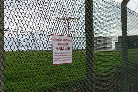BIRMINGHAM INTERNATIONAL AIRPORT, BIRMINGHAM, UNITED KINGDOM - OCTOBER 28, 2017: fence sorrounding the airfield with airport secuity sign and no public access.のeditorial素材