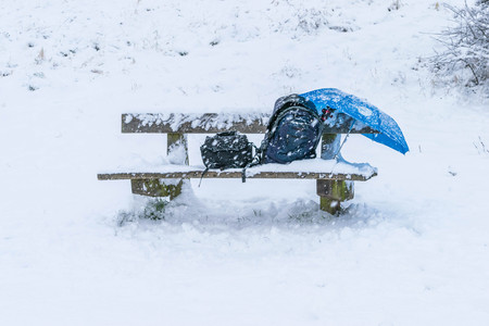 wooden bench chair in a park completely cover with snow after a blizzard during the winter christmas...