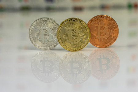 Close up of Bitcoins, gold bitcoin, silver bitcoin and bronze bitcoin with blurred background of world flags. reflection of the bitcoins visible.の写真素材