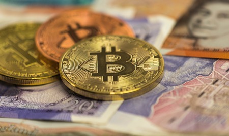 Bitcoins with british banknotes, 20 pounds sterling, 10 pound sterling notes. golden bitcoin, silver bitcoin, bronze bitcoinの写真素材