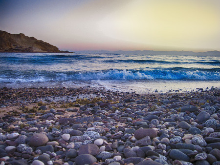 Capture a solitude moment of waves hitting the beach forming a lovely symphony of continuous charm, at an isolated beach, surrounded by the red sea mountains where all magic can come true.の写真素材