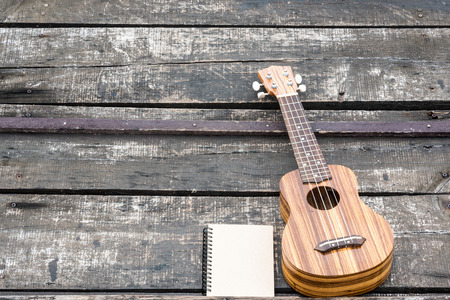 ukulele with the notebook on wood backgroundの写真素材