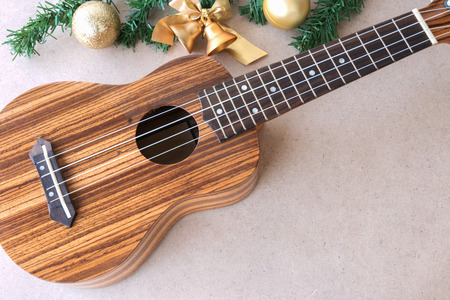 The ukulele on the wooden table with christmas golden decoration, ukulele is a gift from the christmas dayの写真素材
