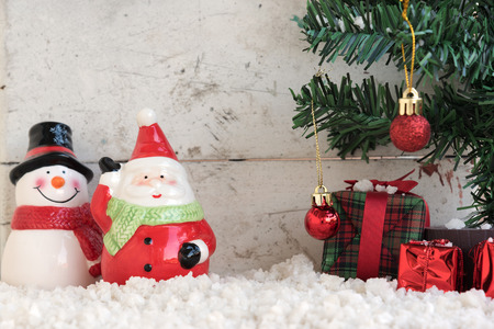 santa claus and snowman on the snow with christmas tree already decorated in vintage backgroundの写真素材