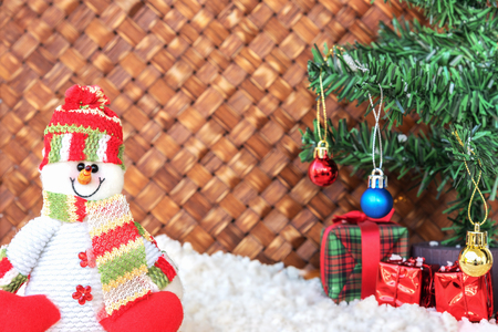 snowman on the snow with christmas tree already decorated in wicker backgroundの写真素材