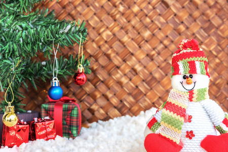snowman on the snow with christmas tree already decorated in wicker backgroundの写真素材
