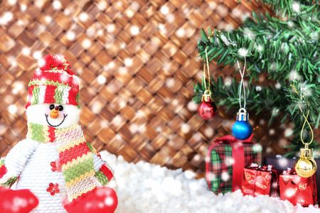 snowman on the snow with christmas tree already decorated in wicker backgroundの写真素材