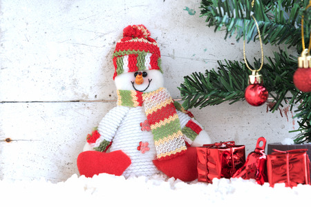 snowman sitting on the snow with christmas tree already decorated in vintage backgroundの写真素材