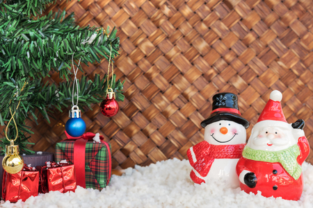 santa claus and snowman on the snow with christmas tree already decorated in wicker backgroundの写真素材