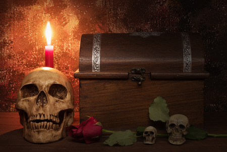 Still life painting photography with human skull, rose, candle and treasure chest on wooden table, dark conceptの写真素材