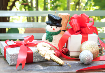 candle snowman, christmas present and ornament over wooden tableの写真素材