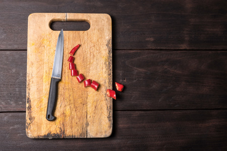 Chilli and knife with chopping block on wooden backgroundの写真素材