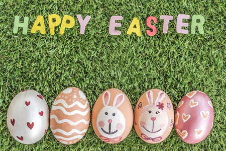 text happy easter word spelling and colorful easter eggs on green grass background, with copy spaceの写真素材