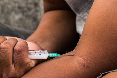 Teenager hand with heroin syringe closeup, narcotic drugs addiction conceptの写真素材