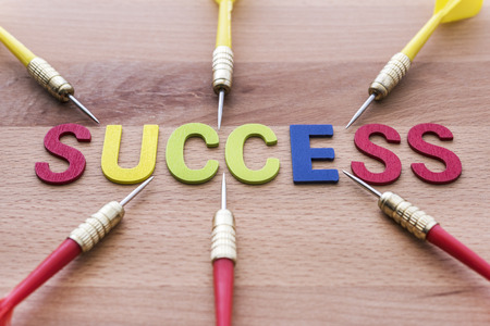 Six dart run in to success target on wooden background. Group of dart (Teamwork) run in to Success target. Abstract success background conceptの写真素材