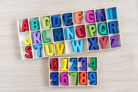 colorful alphabet letters and number in a wooden box with square compartments for teaching kids to read and spell, overhead viewfulの写真素材