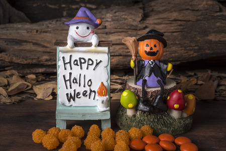 Pumpkin head jack in witch suit sitting on tree with ghost and happy halloween board on forest backgroudの写真素材