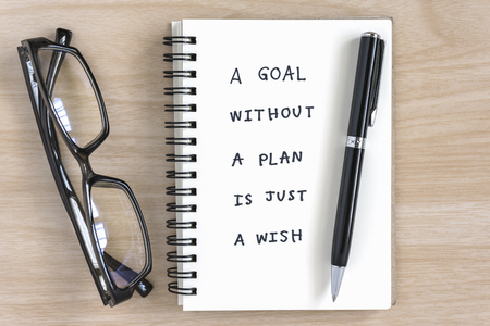 a goal without a plan is just a wish motivational handwriting on a notebook with pen and eye glasses on the deskの写真素材