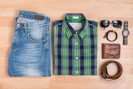 Classic men casual outfits fashionable with accessories on wooden table, Blue and green plaid shirt and jeans with eyeglasses, bracelet, wallet, brown belt and watch, top viewの写真素材