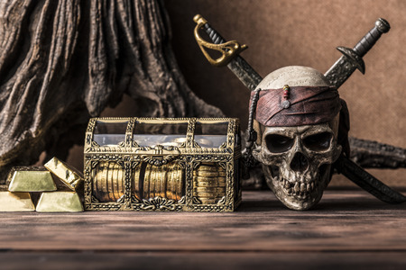still life photography with pirate skull holding two swords and treasure coffer, gold bar,  bullion. Halloween conceptの写真素材