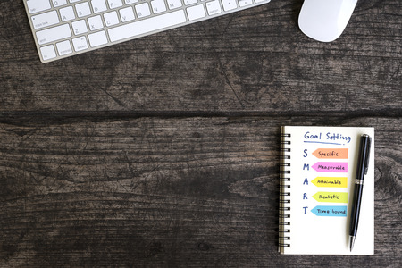 words goal setting smart on open notebook with pen and computer accessories over grungy desk, business conceptの写真素材