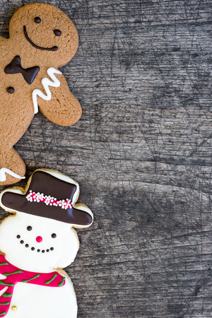 Gingerbread man with snowman cookie on grungy wooden table background with copy space for text,...