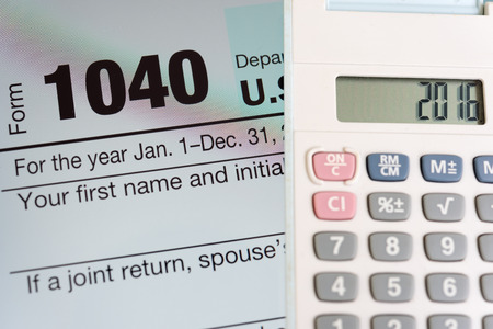 Tax form 1040 on tablet screen and calculator の写真素材