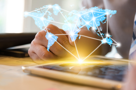 Businessman using computer tablet and finger touching screen with orange light and show blue world map with network conncection line, technology conceptual, internet globalization conceptの写真素材