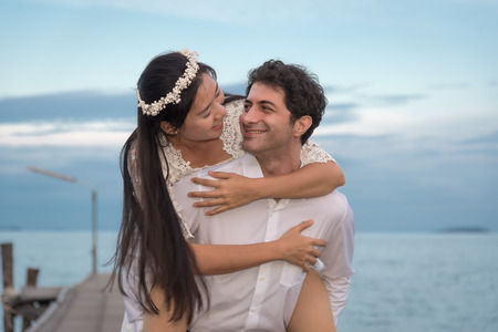 Young love Couple smiling under blue sky on wooden bridge near the seaの写真素材