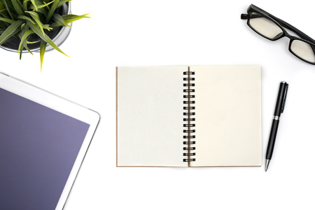 Modern white office desk table with computer tablet, pen, eye glasses and blank notebook page for input the text in the middle. Top view, flat lay.の写真素材