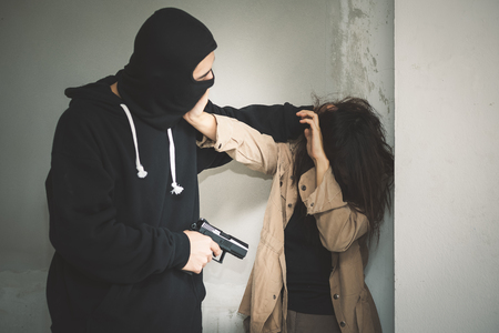 Hostage of terrorist or burglar threatening with gun in abandoned buildingの写真素材