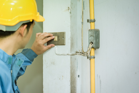 Young electrician checking old switch inside building, Technician conceptの写真素材
