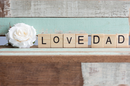 Love dad words with white rose on rustic vintage table over wooden retro background, Metaphor true...