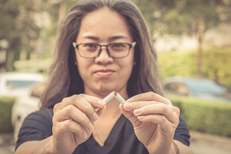 Woman break down cigarette and winning with addicted nicotine problems, stop smoking conceptual. Quitting from addiction concept. の写真素材