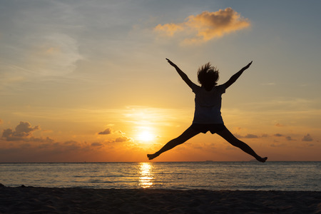 Freedom concept with silhouette young teenager happy and jump on a beautiful sunset at the beachの写真素材