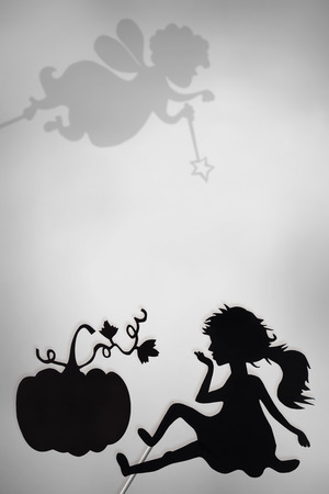 Cinderella and Pumpkin shadow puppets and shades of Fairy Godmother on the screen of shadow theater, copy space background, black and white.の写真素材