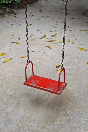 Red wooden swing hanging on chainsの写真素材
