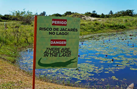 Rio de Janeiro, Brazil - December 16, 2019: Signboard warning the danger of alligators in the lake....