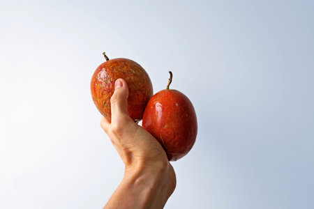 Red Passion fruits on hand on a bright background