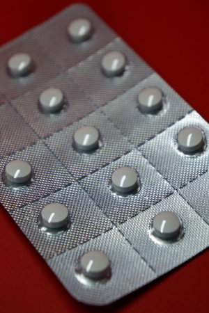 Blister pack of white pills on red background