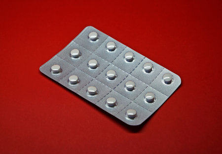 Blister pack of white pills on red backgroundの写真素材